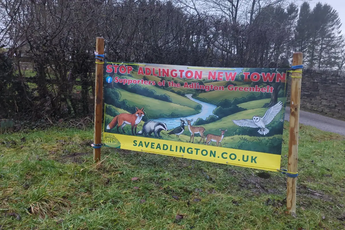 A banner depicting countryside turning into house construction. Caption From Greenbelt to Grey Profits?