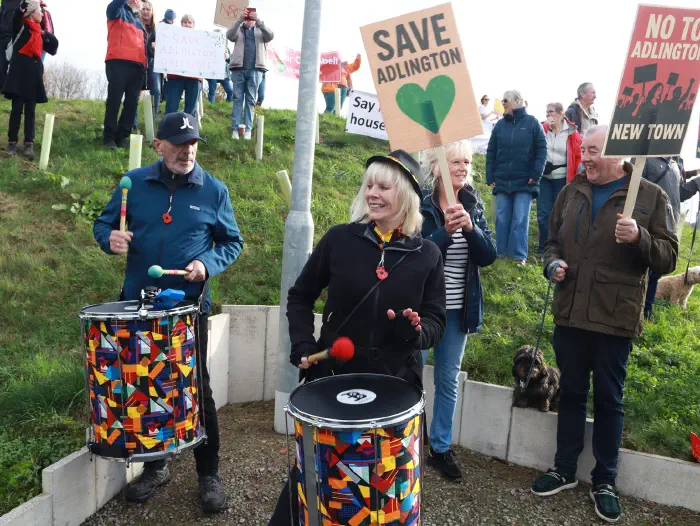 Drummers playing in front of people holding Save Adlington placards