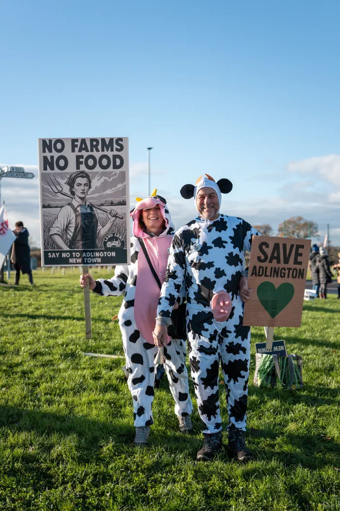 Couple dressed as cows holding No Farms No Food and Save Adlington placards