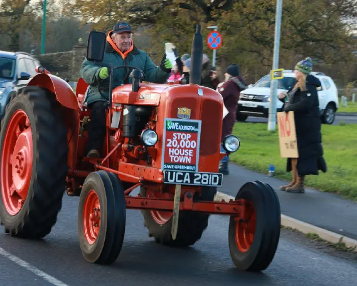 Red vintage tractor displaying Save Adlington placard