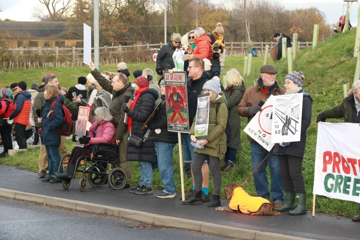 Protesters gathered on hillside holding placards