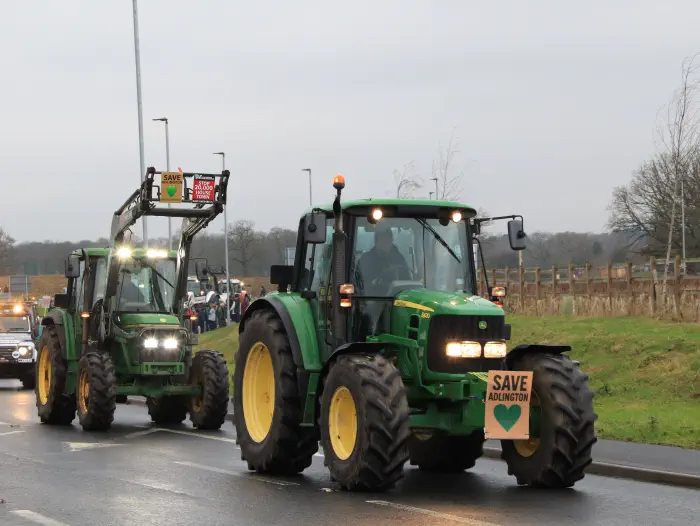2 green tractors with placards at protest