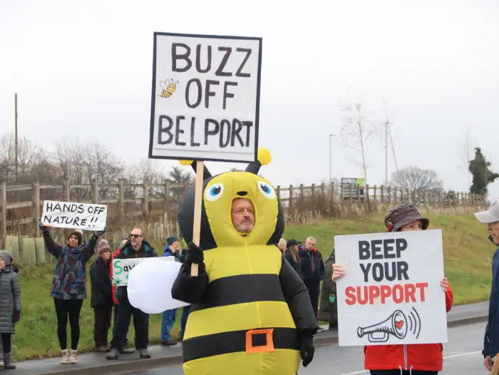 Bee holding sign saying Buzz off Belport