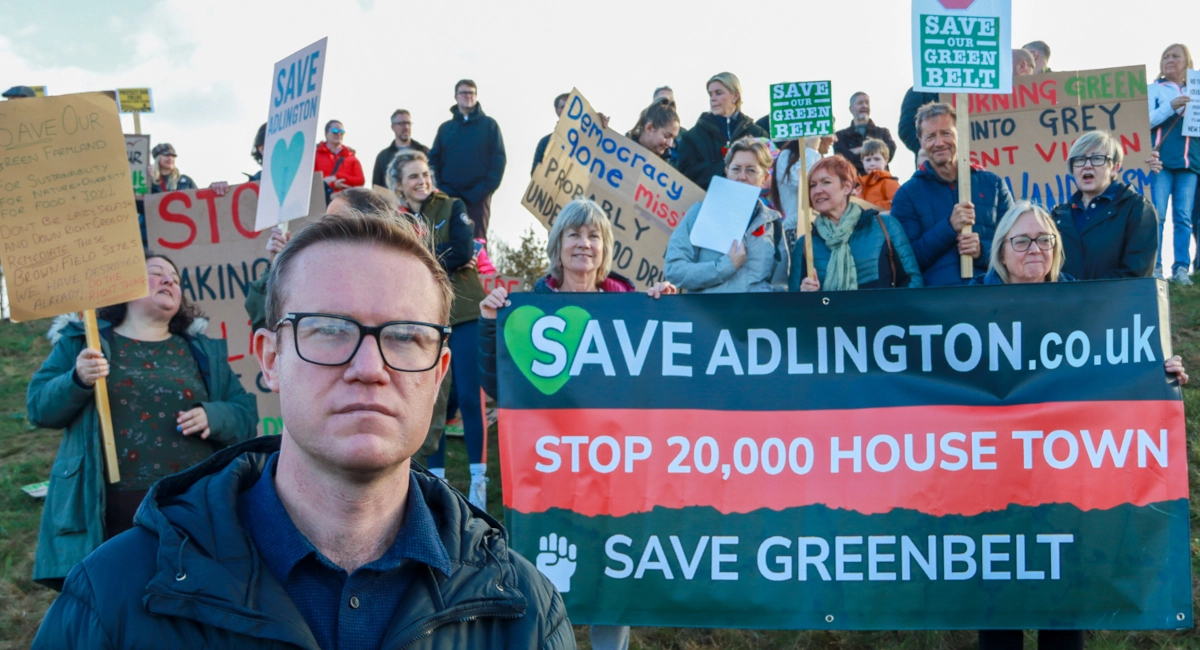 Tim Roca MP standing in front of a Save Adlington banner
